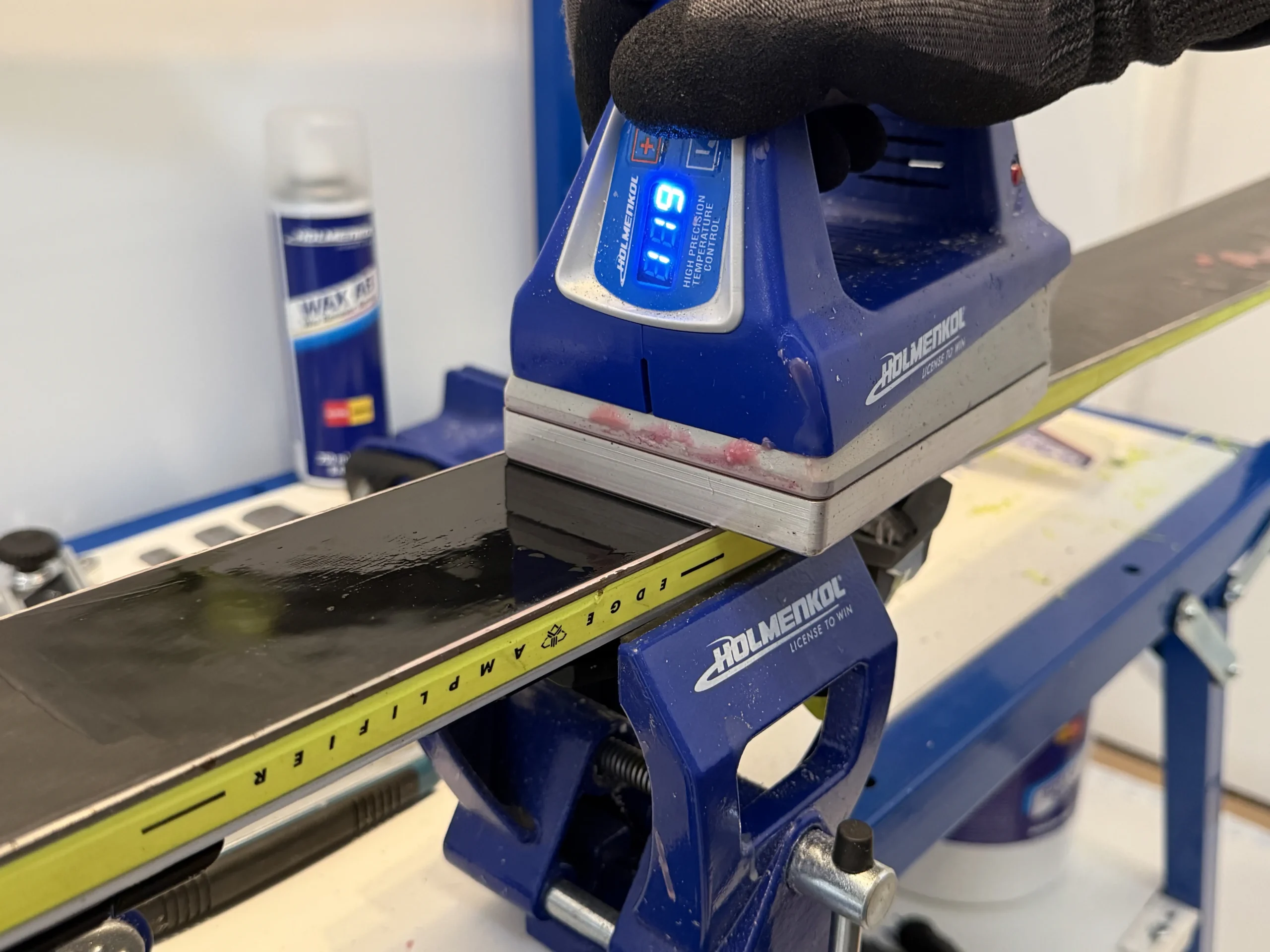 Waxijzer dat hot wax verdeelt over het belag van een ski