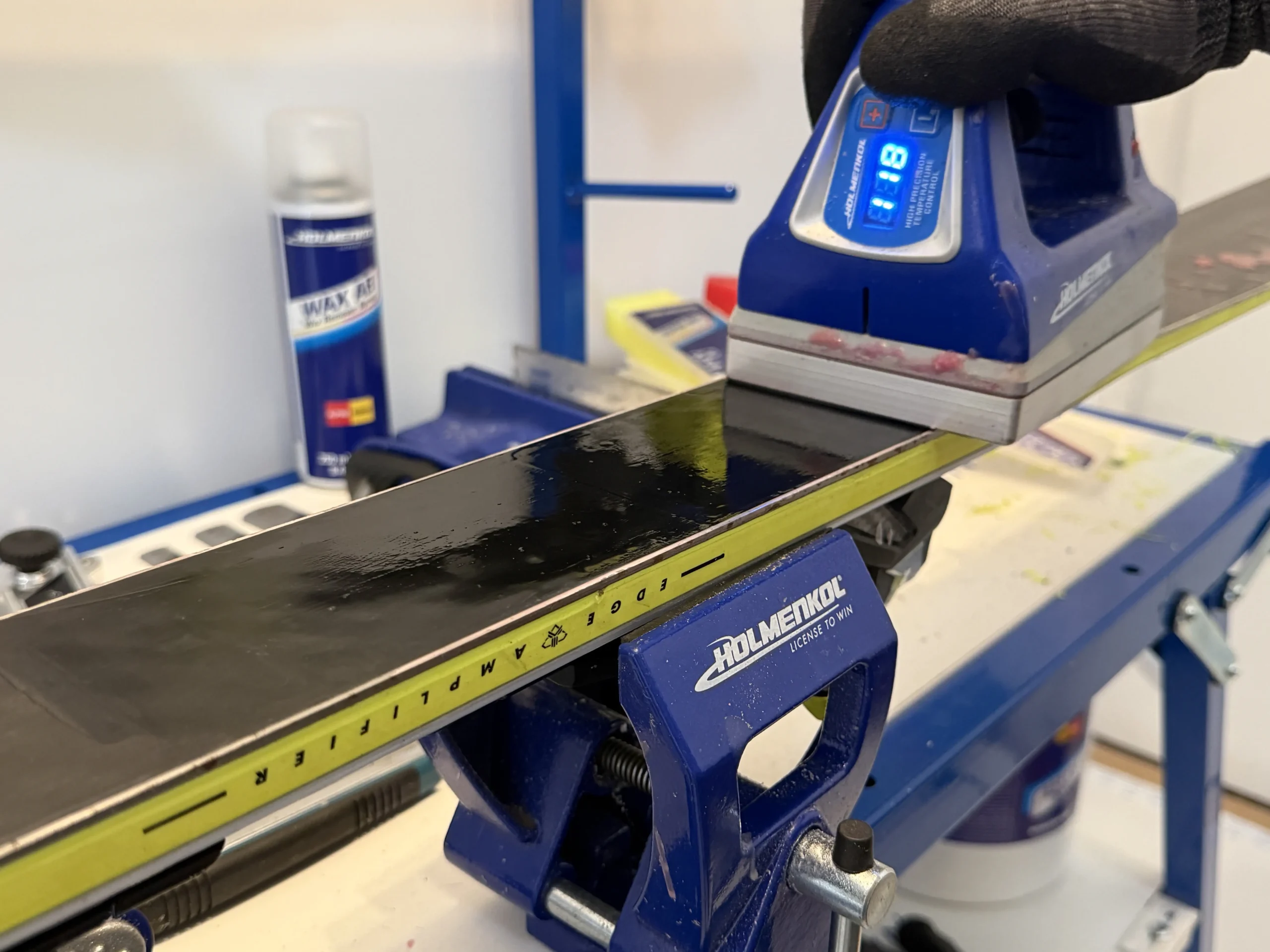 Hot wax wordt met een waxijzer aangebracht op een ski tijdens ski onderhoud voor Etten-Leur