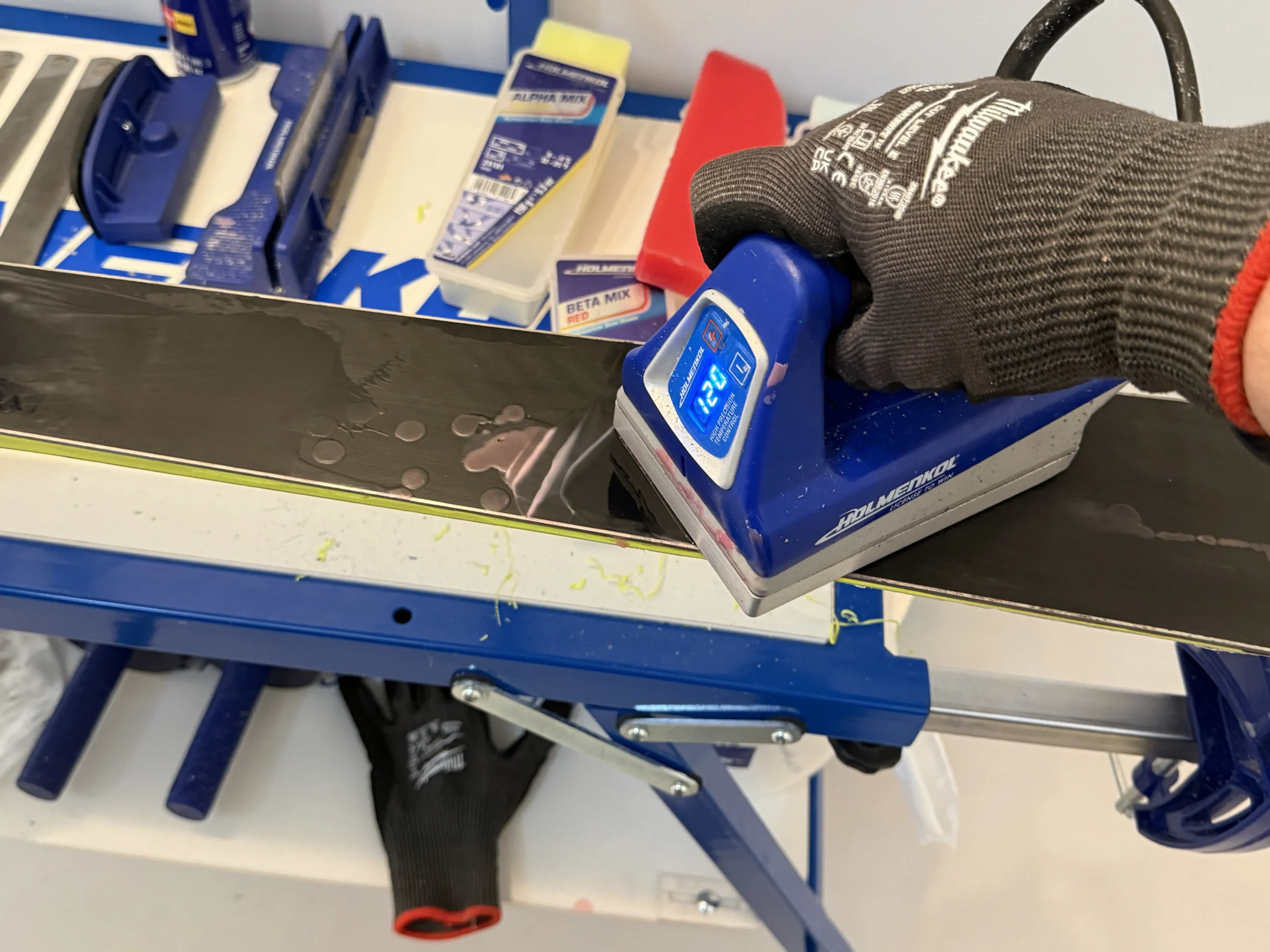 Waxijzer dat hot wax aanbrengt op een ski tijdens ski onderhoud