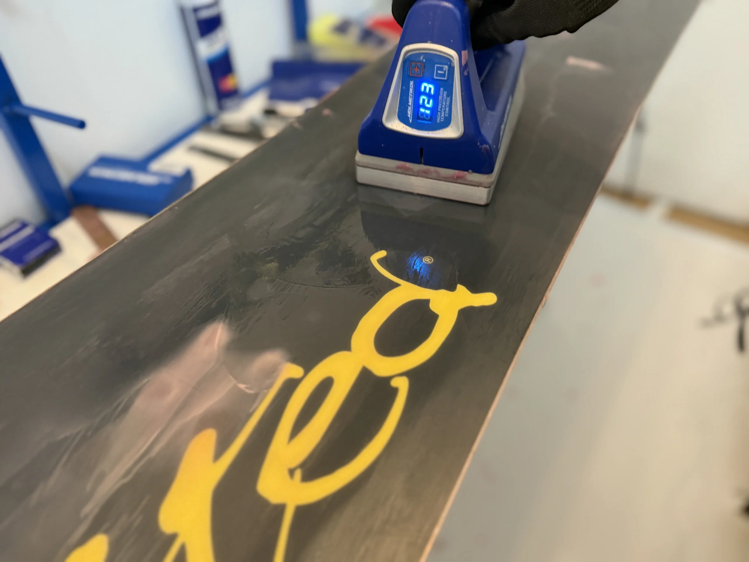 Hot wax druppelt op snowboard met waxijzer tijdens snowboard onderhoud in Terheijden