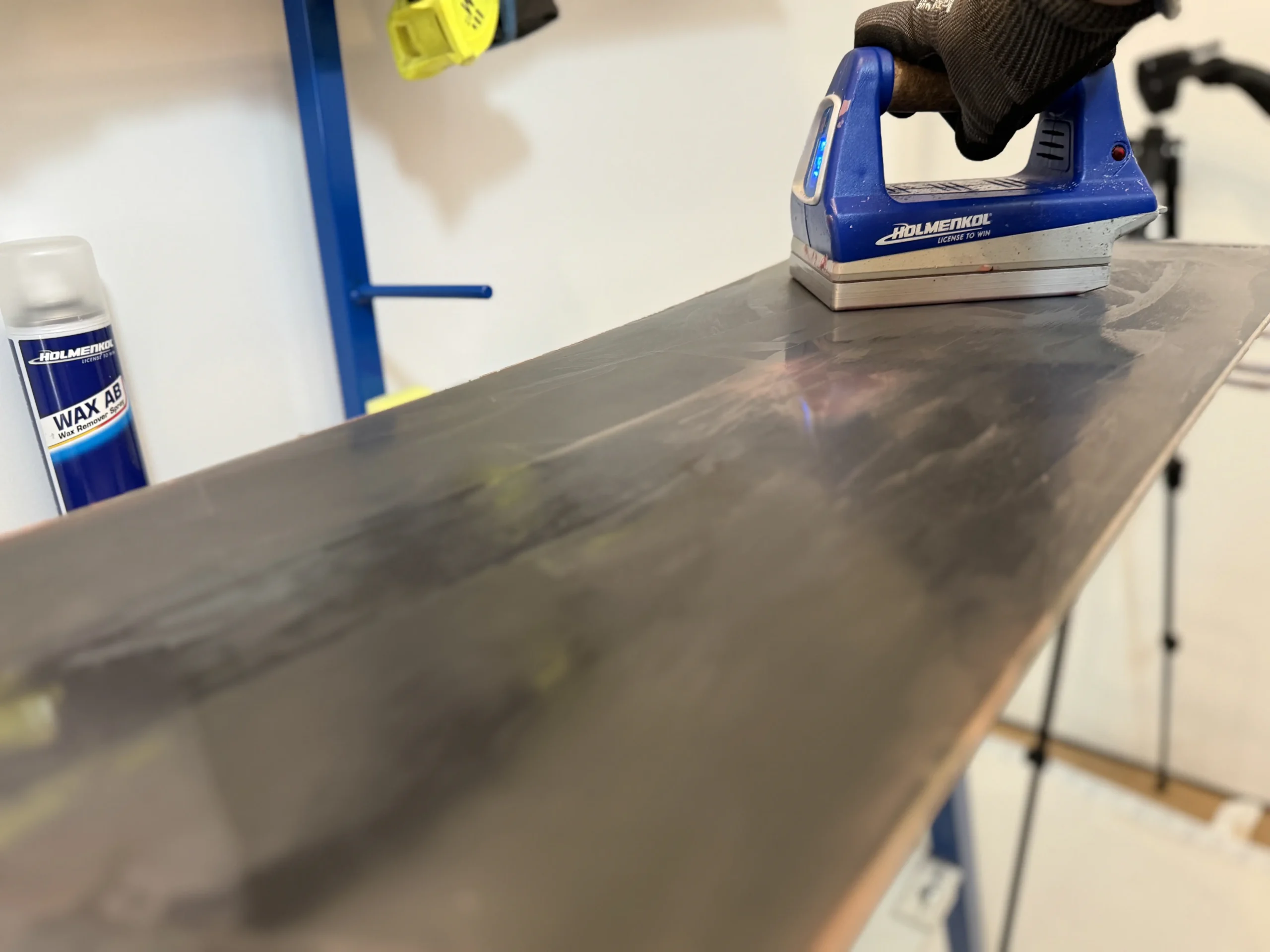 Waxijzer brengt hot wax aan op snowboard tijdens snowboard onderhoud voor Prinsenbeek